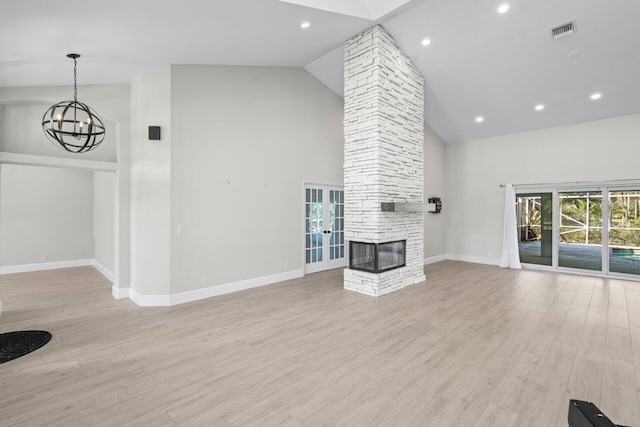 unfurnished living room featuring visible vents, baseboards, light wood-style flooring, an inviting chandelier, and a stone fireplace