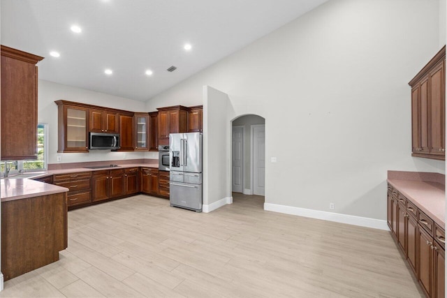 kitchen featuring arched walkways, stainless steel appliances, light countertops, visible vents, and glass insert cabinets