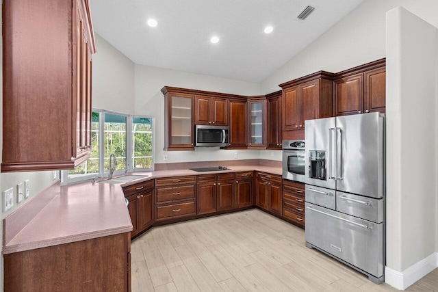 kitchen featuring stainless steel appliances, light countertops, visible vents, glass insert cabinets, and a sink