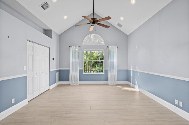 spare room with high vaulted ceiling, light wood-style flooring, visible vents, and baseboards