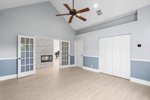 unfurnished living room with ceiling fan, a fireplace, visible vents, light wood-style floors, and french doors