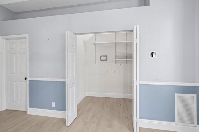 laundry room featuring light wood-type flooring, visible vents, and baseboards