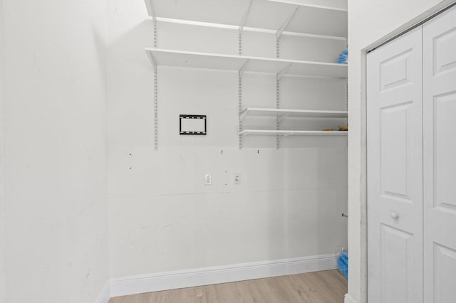 clothes washing area with baseboards and wood finished floors