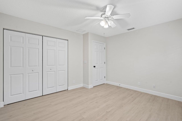 unfurnished bedroom featuring light wood-type flooring, baseboards, visible vents, and a closet