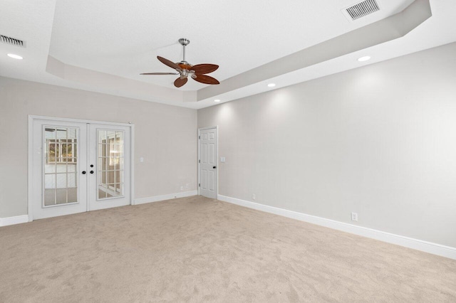 unfurnished room with visible vents, a tray ceiling, baseboards, and french doors