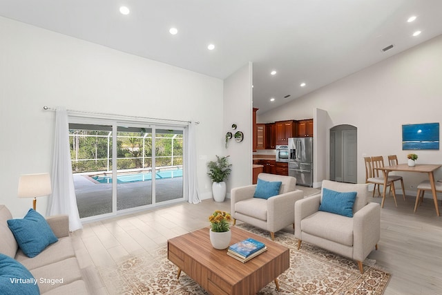 living room featuring arched walkways, high vaulted ceiling, recessed lighting, visible vents, and light wood finished floors