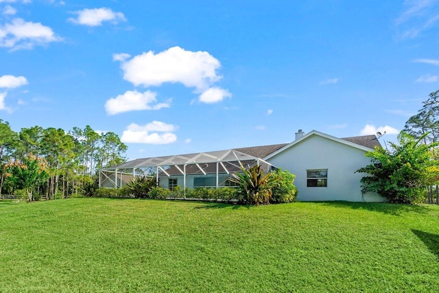 back of house featuring a yard, a lanai, and stucco siding