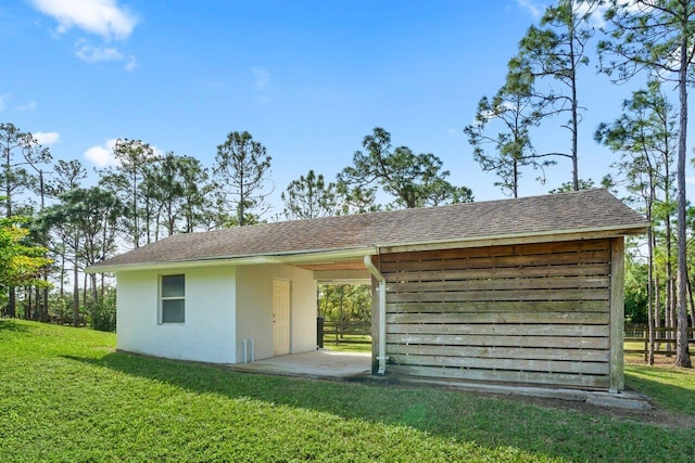 exterior space with a shingled roof, a lawn, and stucco siding