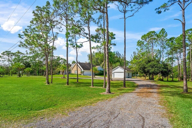 surrounding community with driveway, a detached garage, and a yard