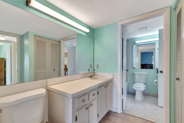 bathroom with visible vents, toilet, tile patterned flooring, vanity, and a closet