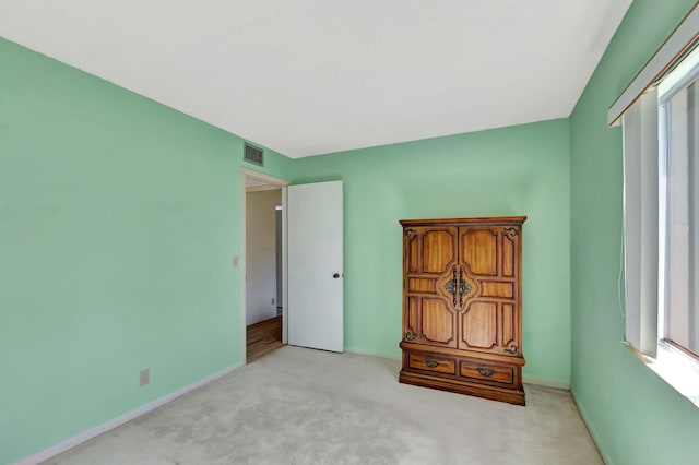 unfurnished bedroom with light colored carpet, visible vents, and baseboards