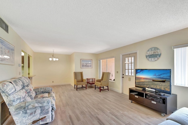 living area with a chandelier, light wood-type flooring, and a textured ceiling