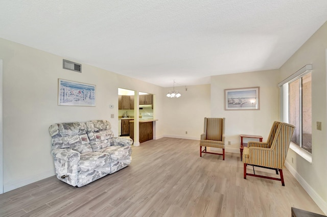 sitting room with visible vents, light wood-style flooring, and baseboards