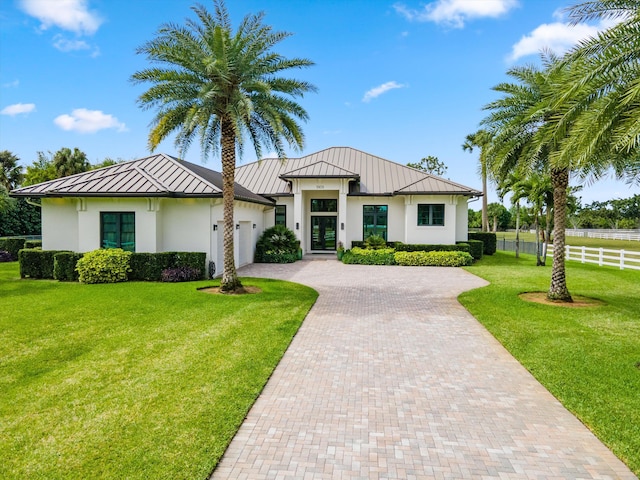 view of front facade with metal roof, an attached garage, fence, decorative driveway, and a standing seam roof