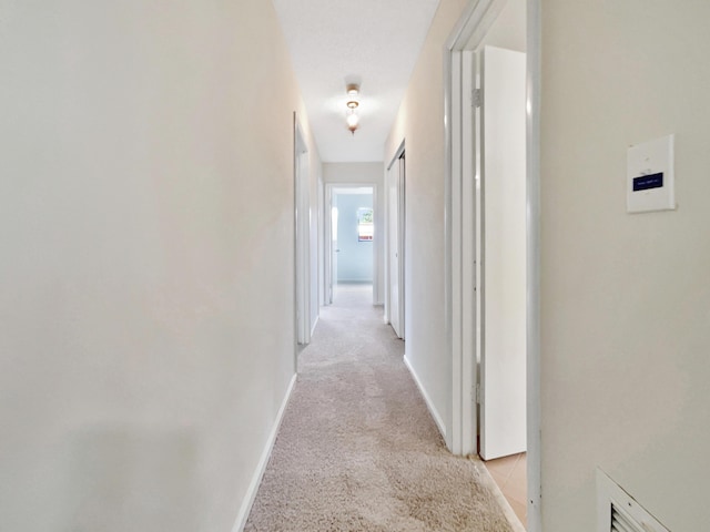 hall featuring light carpet and baseboards