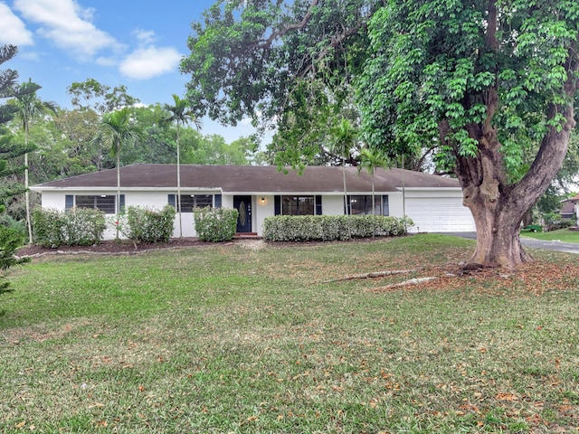 ranch-style home featuring a garage, driveway, and a front lawn