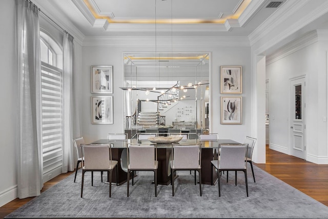 dining space with baseboards, a tray ceiling, ornamental molding, an inviting chandelier, and wood finished floors