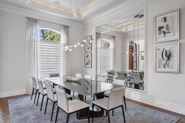 dining space featuring wood finished floors, baseboards, an inviting chandelier, a tray ceiling, and ornamental molding