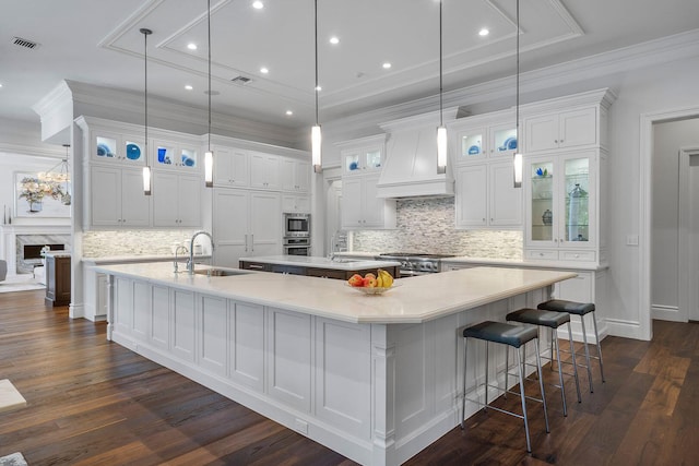 kitchen featuring visible vents, a large island, custom range hood, a sink, and stainless steel range with gas stovetop