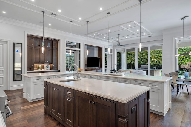 kitchen featuring visible vents, a large island with sink, ceiling fan, and a sink