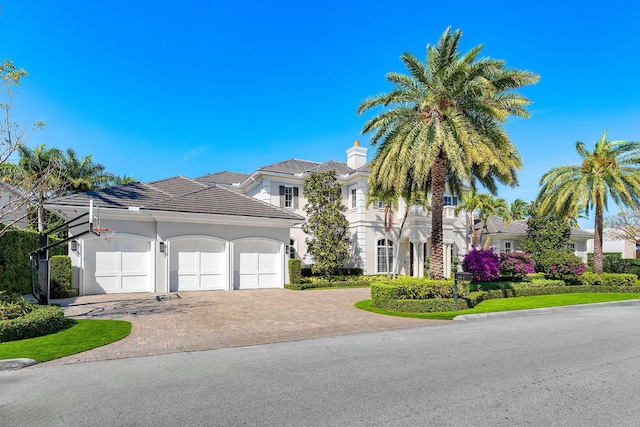 view of front facade with stucco siding, decorative driveway, and a garage