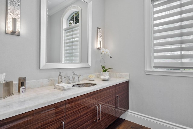 bathroom featuring baseboards, wood finished floors, vanity, and ornamental molding