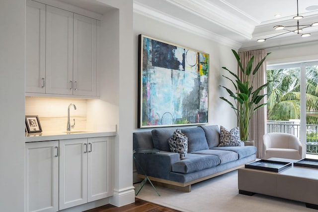 living area with ornamental molding, recessed lighting, wet bar, wood finished floors, and a raised ceiling