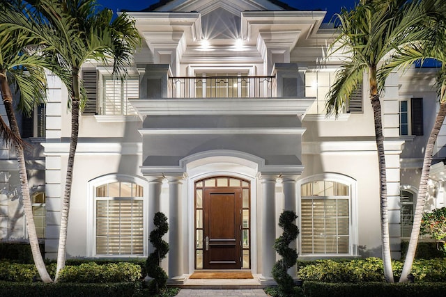 entrance to property with stucco siding and a balcony