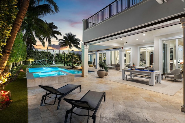 pool at dusk with an outdoor pool and a patio area