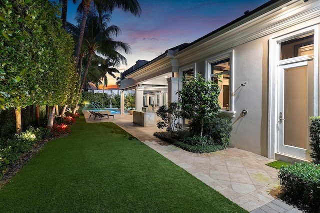 yard at dusk featuring an outdoor pool and a patio