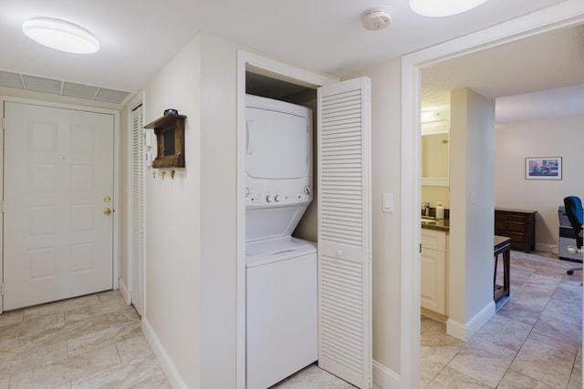 laundry area with laundry area, visible vents, baseboards, and stacked washing maching and dryer