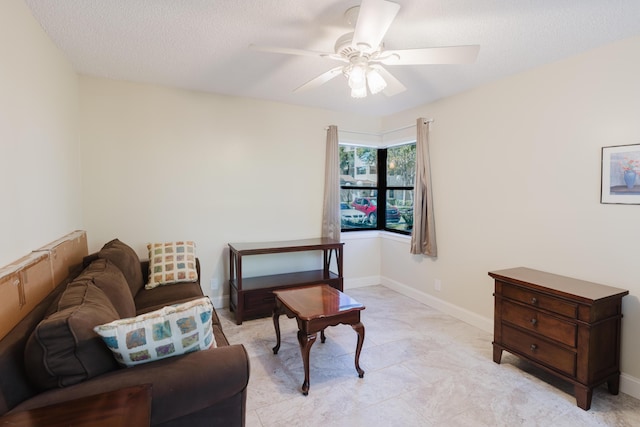 sitting room featuring ceiling fan, a textured ceiling, and baseboards