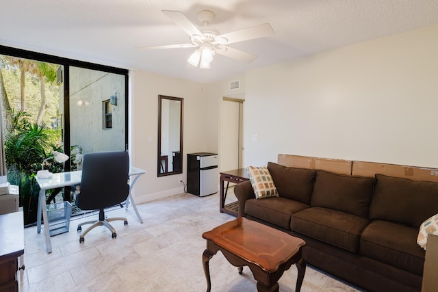 office space featuring visible vents, a ceiling fan, expansive windows, a textured ceiling, and baseboards