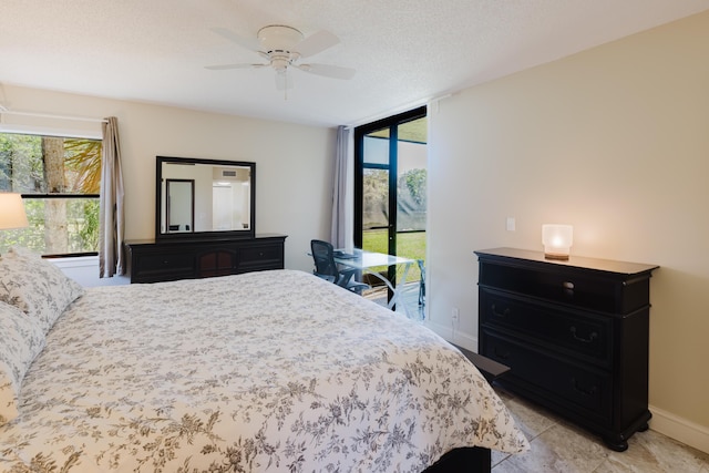 bedroom featuring a ceiling fan, floor to ceiling windows, baseboards, and a textured ceiling