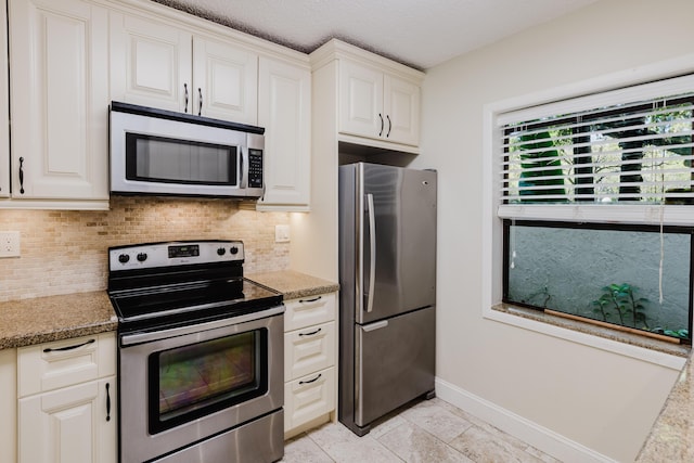 kitchen featuring appliances with stainless steel finishes, white cabinetry, backsplash, and baseboards