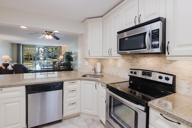 kitchen featuring white cabinets, backsplash, stainless steel appliances, and a sink