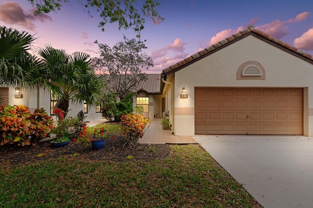 mediterranean / spanish home featuring a tile roof, stucco siding, an attached garage, and concrete driveway