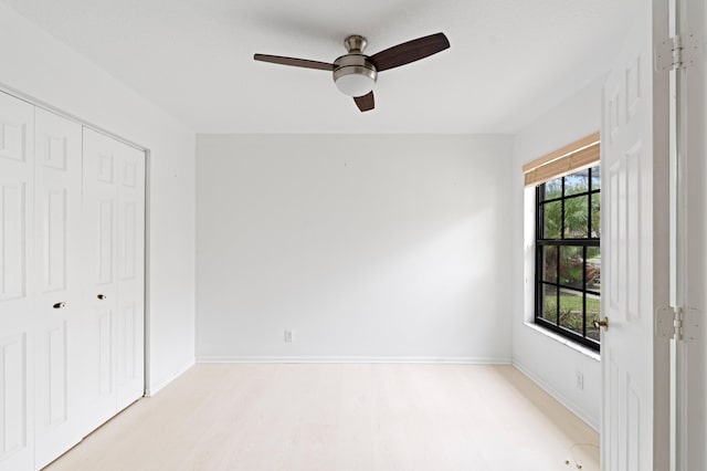 unfurnished bedroom featuring a closet, baseboards, light wood-style floors, and ceiling fan