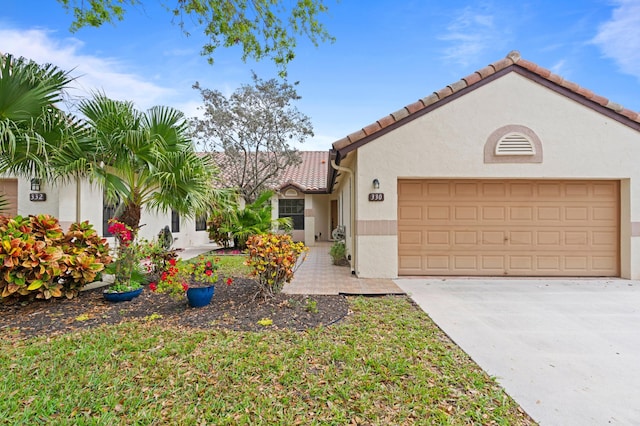 mediterranean / spanish house with stucco siding, a tiled roof, concrete driveway, and an attached garage