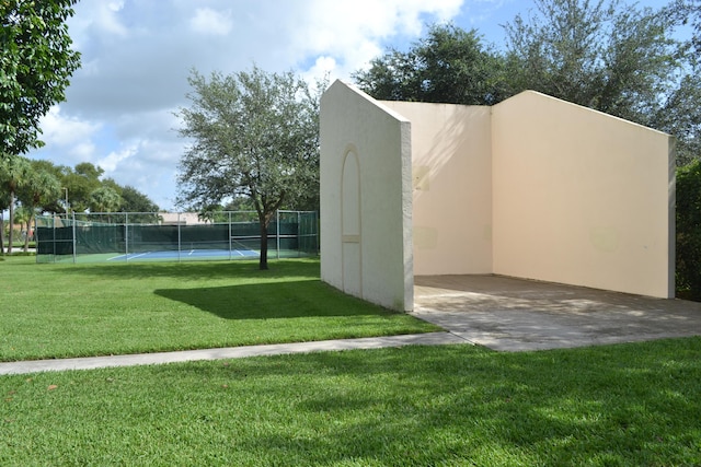 view of community featuring a tennis court, a lawn, and fence