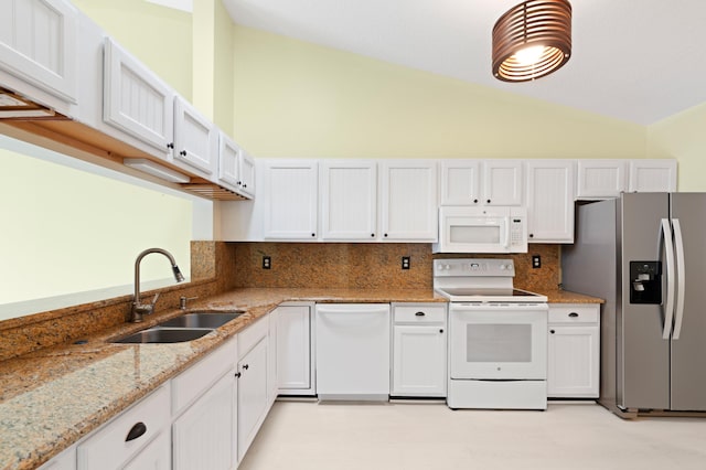 kitchen with tasteful backsplash, light stone countertops, vaulted ceiling, white appliances, and a sink