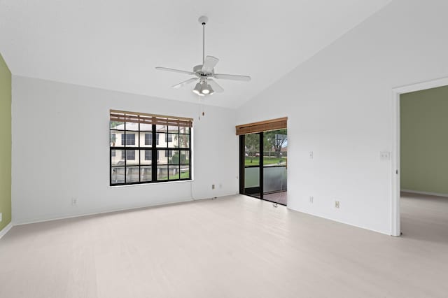 spare room with wood finished floors, a ceiling fan, baseboards, and high vaulted ceiling