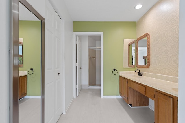 full bathroom featuring a sink, recessed lighting, wallpapered walls, double vanity, and baseboards