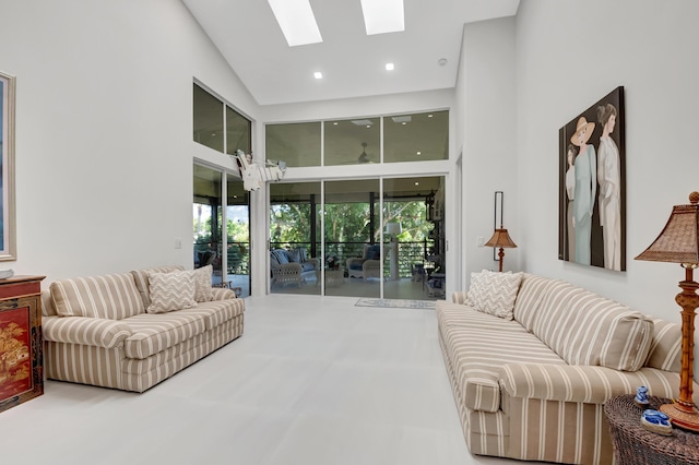 living area featuring a skylight, a towering ceiling, and recessed lighting