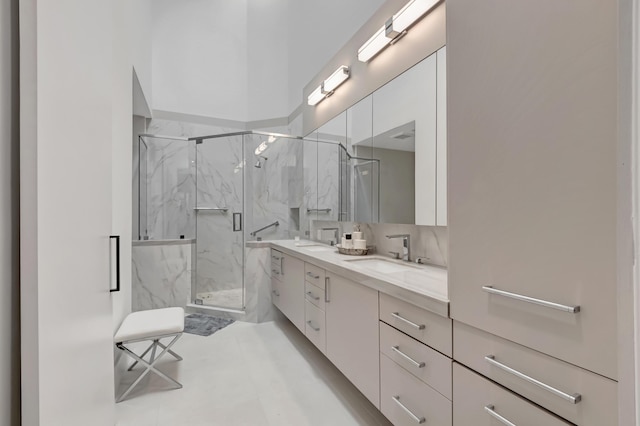 full bathroom featuring double vanity, a marble finish shower, and a sink