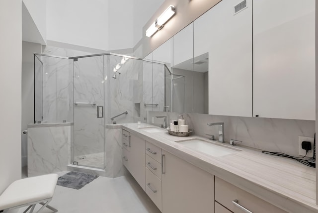 full bathroom with a marble finish shower, a sink, and visible vents