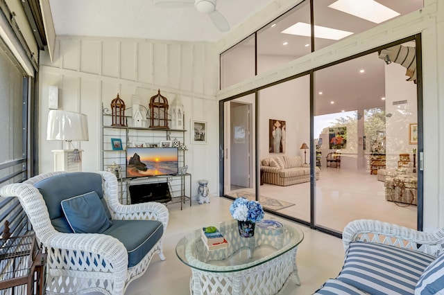 living room featuring finished concrete floors, a sunroom, ceiling fan, and a towering ceiling