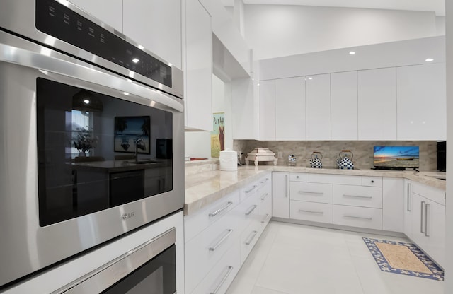 kitchen featuring light stone countertops, tasteful backsplash, modern cabinets, and white cabinetry