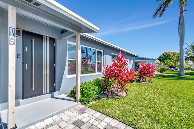 view of exterior entry featuring a yard and stucco siding