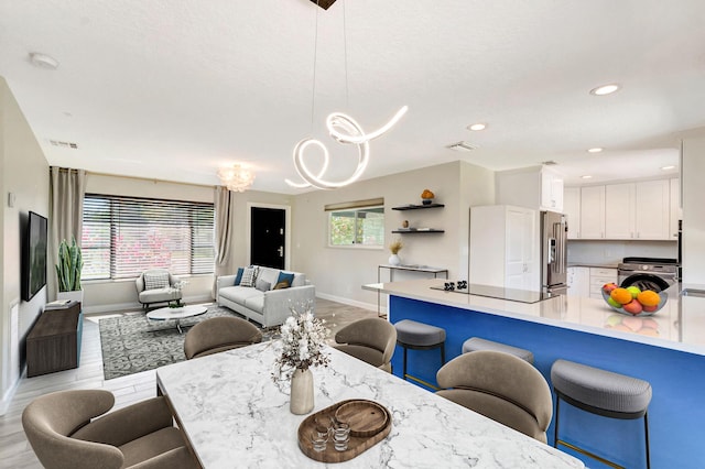 dining area with visible vents, baseboards, light wood finished floors, washer / dryer, and a notable chandelier